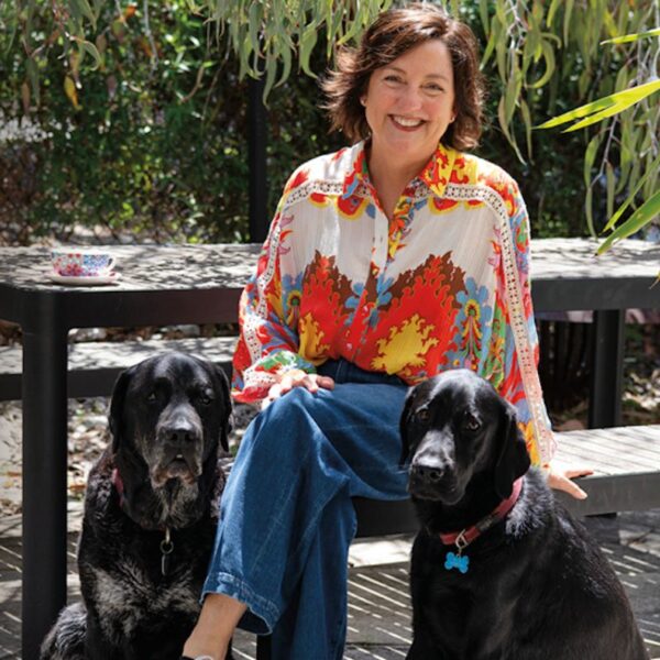 Suzie Hunt sitting on a bench with her two dogs be her side.